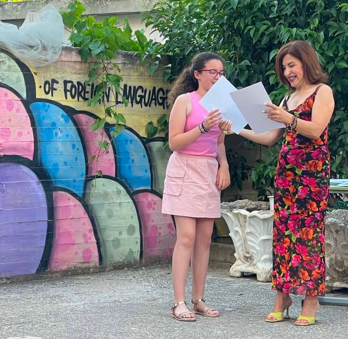 Μαθήτρια δείχνει το αναμνηστικό της δίπλα σε εκπαιδευτικό.