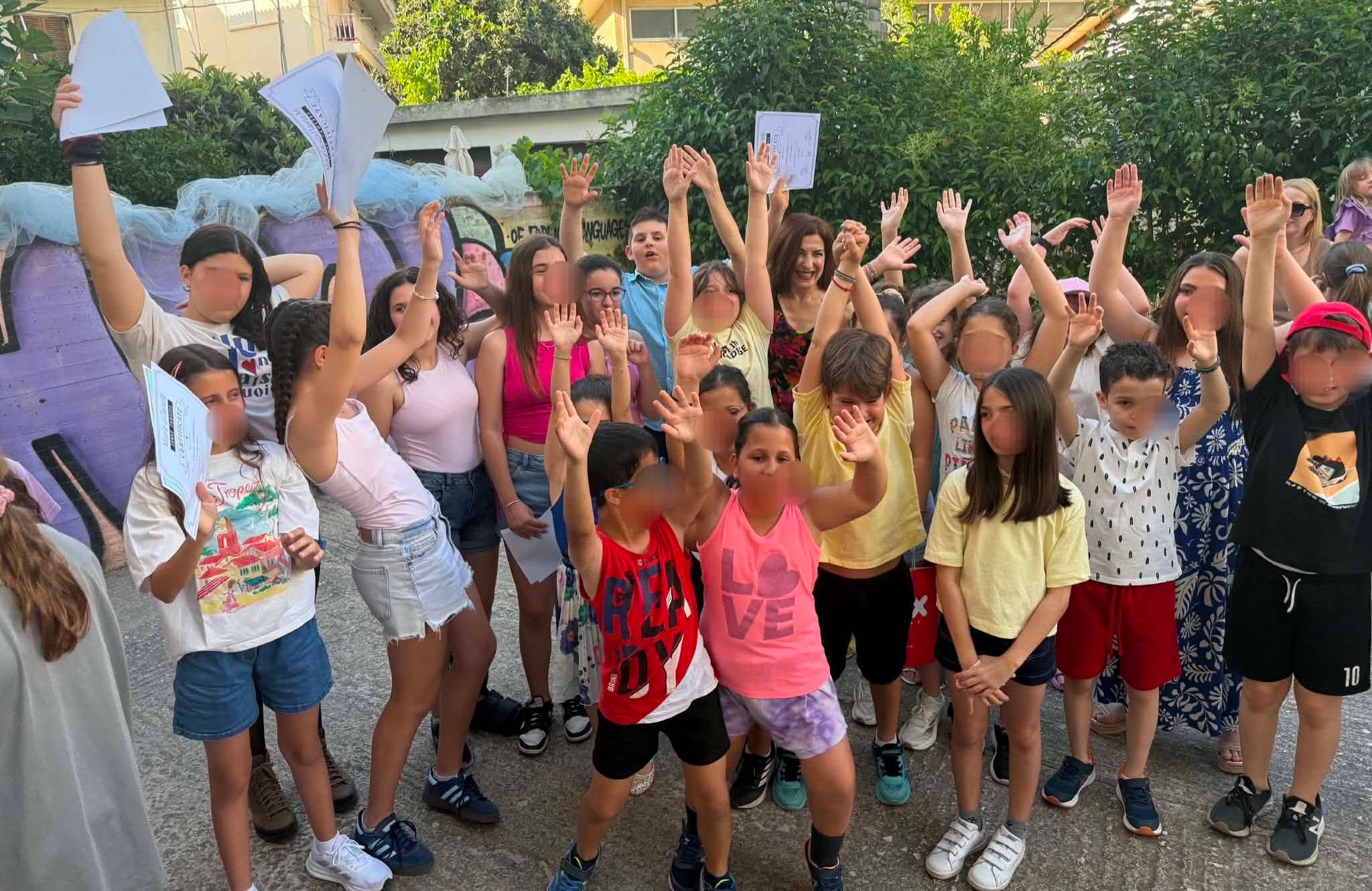 Ομάδα μαθητών σηκώνει τις εργασίες της στο προαύλιο.
