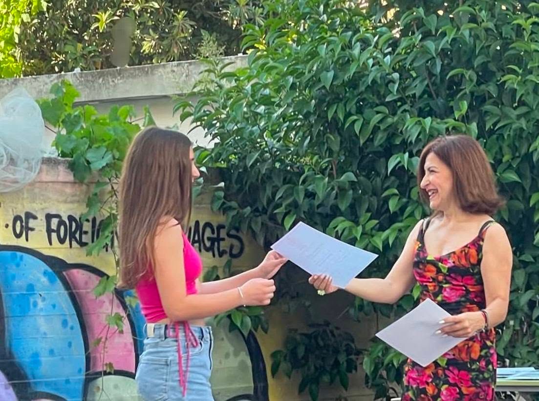 Μαθήτρια και εκπαιδευτικός παρουσιάζουν εργασία στο προαύλιο.