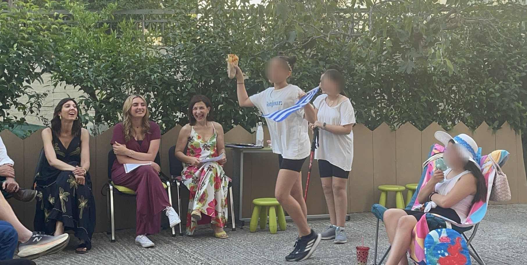 Εκπαιδευτικοί και μαθητές παρακολουθούν παρουσίαση στο προαύλιο.
